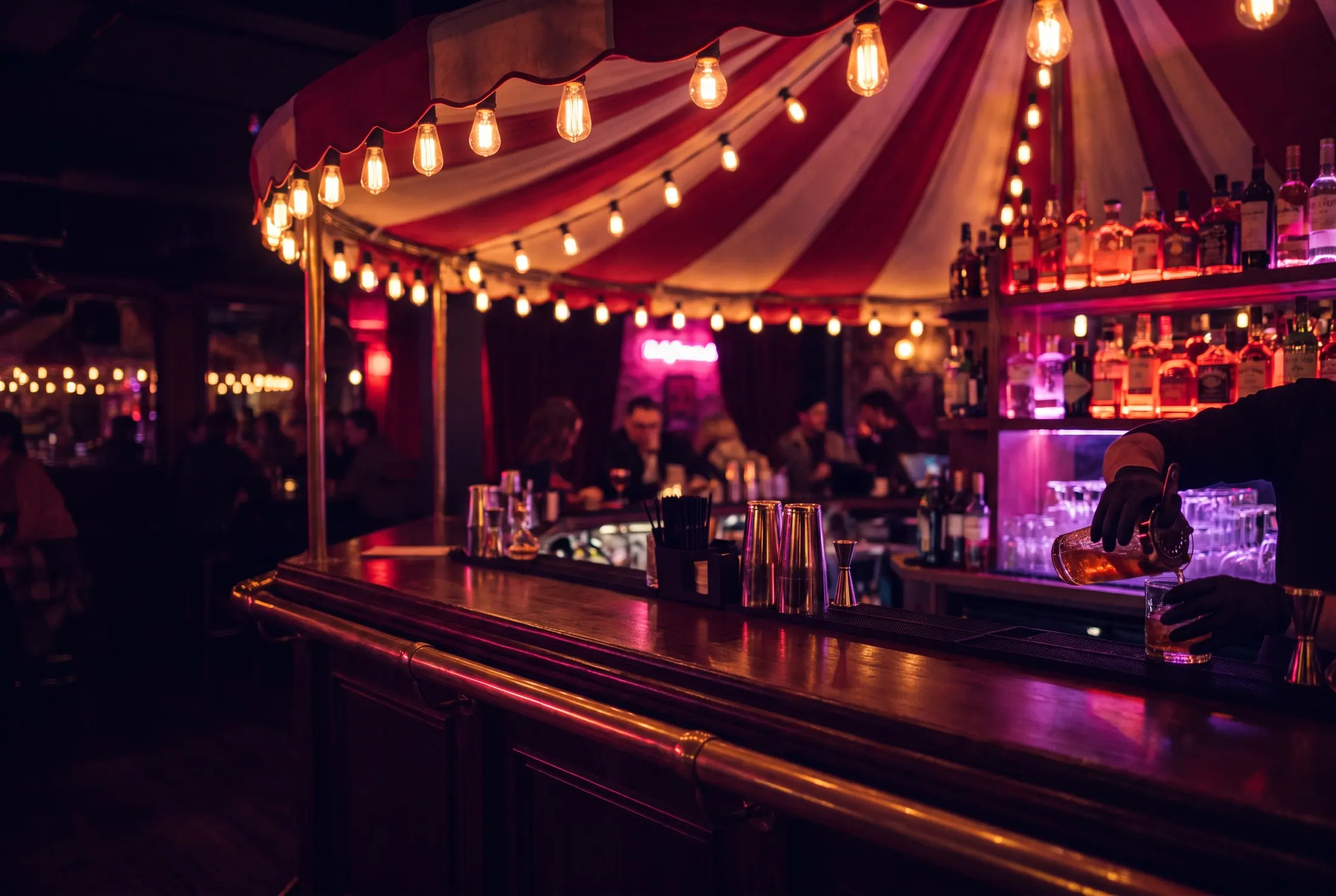 Le comptoir du Carrousel sous la marquise rayée, bouteilles rétroéclairées et ampoules dorées